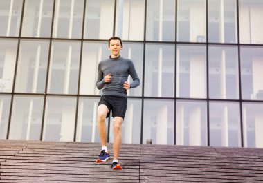 Aşağı gidiş spor giyim yakışıklı genç adamın tam uzunlukta şehir merdivenlerde açık havada onun iş parçası olarak