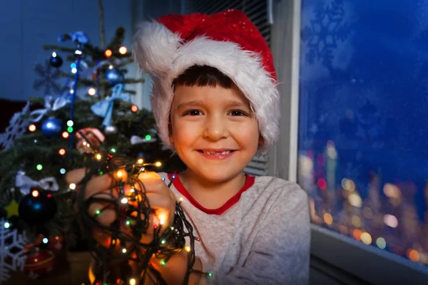 Menino Chapéu Santa Rindo Sorrindo Segurando Luzes Iluminação Ano Novo — Fotografia de Stock