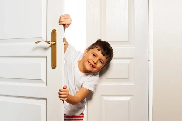 漂亮英俊的男孩打开好奇的白色门在家里 挂看相机 — 图库照片