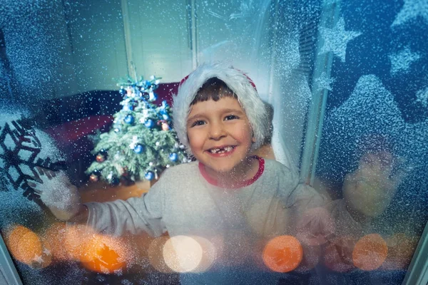 Junge Mit Weihnachtlichem Gesichtsausdruck Weihnachtsmannmütze Der Nähe Des Neujahrsbaumes Hinter — Stockfoto