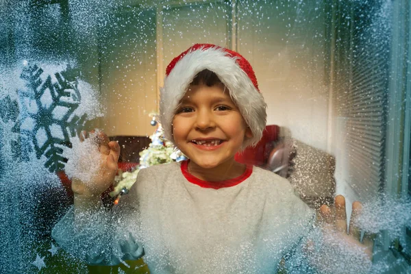 Portret Van Gelukkig Jongetje Zoek Frosty Venster Santa Hat Met — Stockfoto