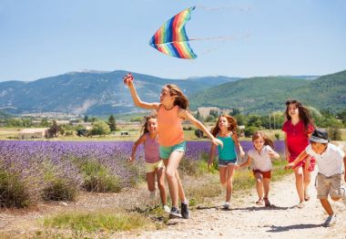 Yaş-çeşitli çocuklar eğleniyor büyük grup yaz aylarında gökkuşağı uçurtma uçan