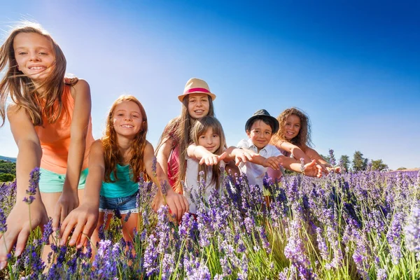 Group of happy preteen boy and girls standing in lavender fields, Provence reaching their hands out
