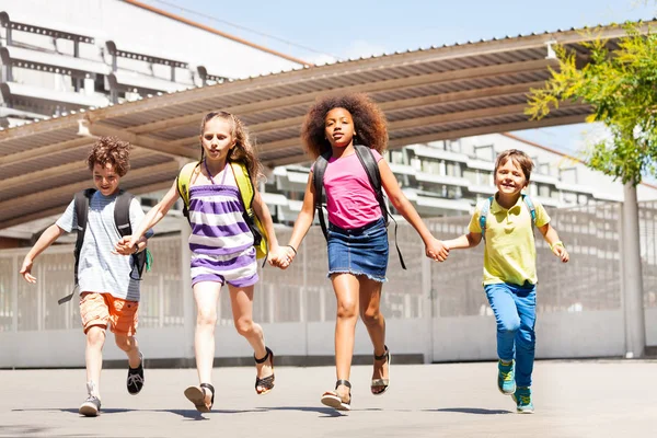 男孩和女孩跑在学校庭院前面愉快的牵手微笑 — 图库照片