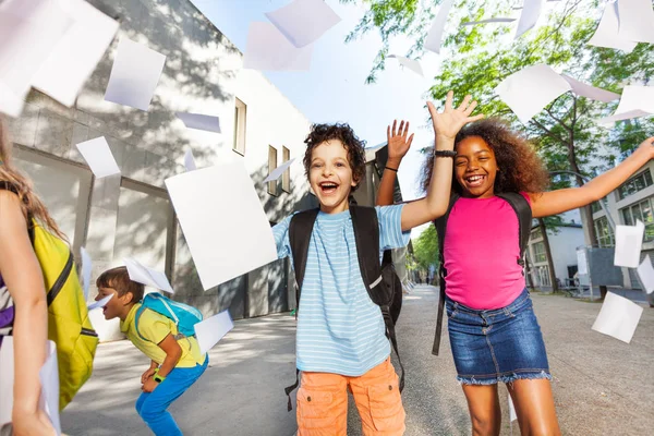 Счастливый Взволнованный Мальчик Бросает Бумаги Воздух Друзьями Возле Школьной Двери — стоковое фото