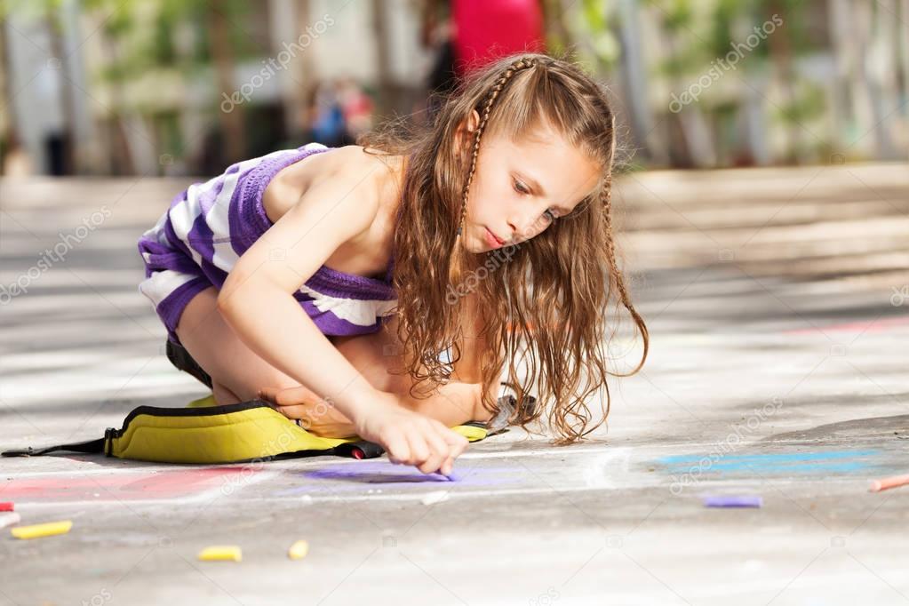 Close portrait of a beautiful girl draw with chalk on the asphalt