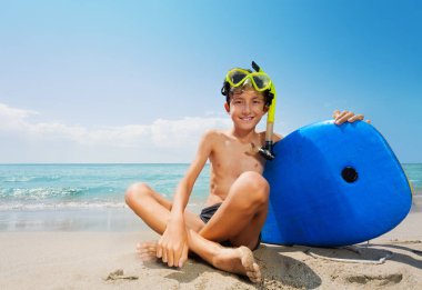 Çocuk beden ile yönetim kurulu için dalga köpüğü ve inç tüplü maske oturmak deniz plaj tatil sırasında