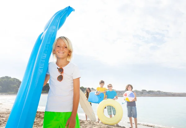 Loira Bonito Garoto Com Amigos Praia Areia Segurando Azul Matrass — Fotografia de Stock