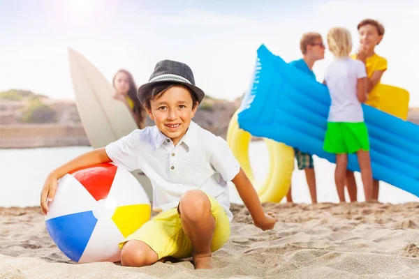 Niño Feliz Sentado Pelota Playa Sus Amigos Cerca Del Mar —  Fotos de Stock
