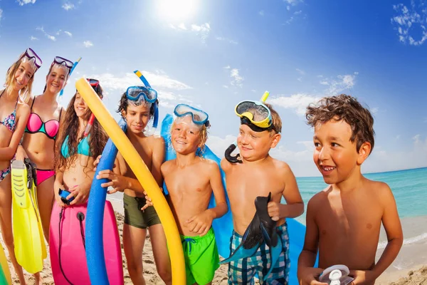 快乐的男孩和女孩游泳西装站在海滩上炎热的夏日假期穿着潜水口罩 手持游泳棍或鳍 — 图库照片