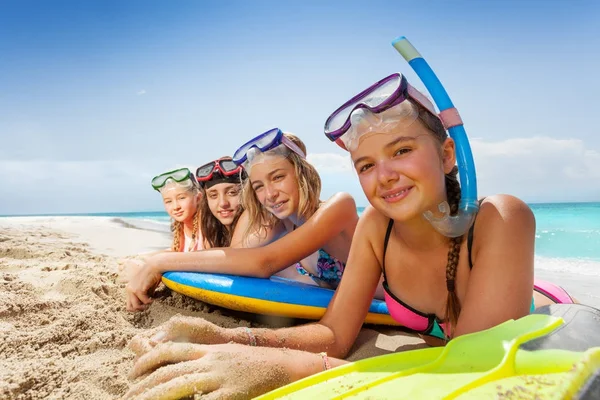 Cute girls laying with body boards on sandy beach, relaxing and tanning after snorkeling