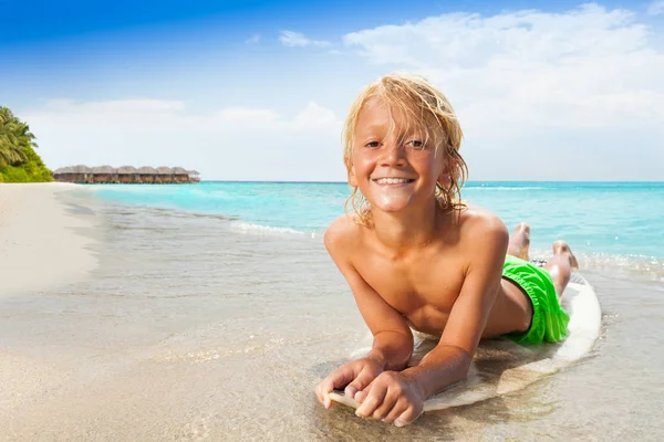 Little blond boy laying on surfboard on the beach smiling happy — Stock Image Little Blond Boy Laying Surfboard Beach Smiling Happy Royalty Free Stock Images