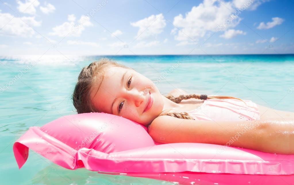 Happy little girl portrait on the matrass resting on the sea waves