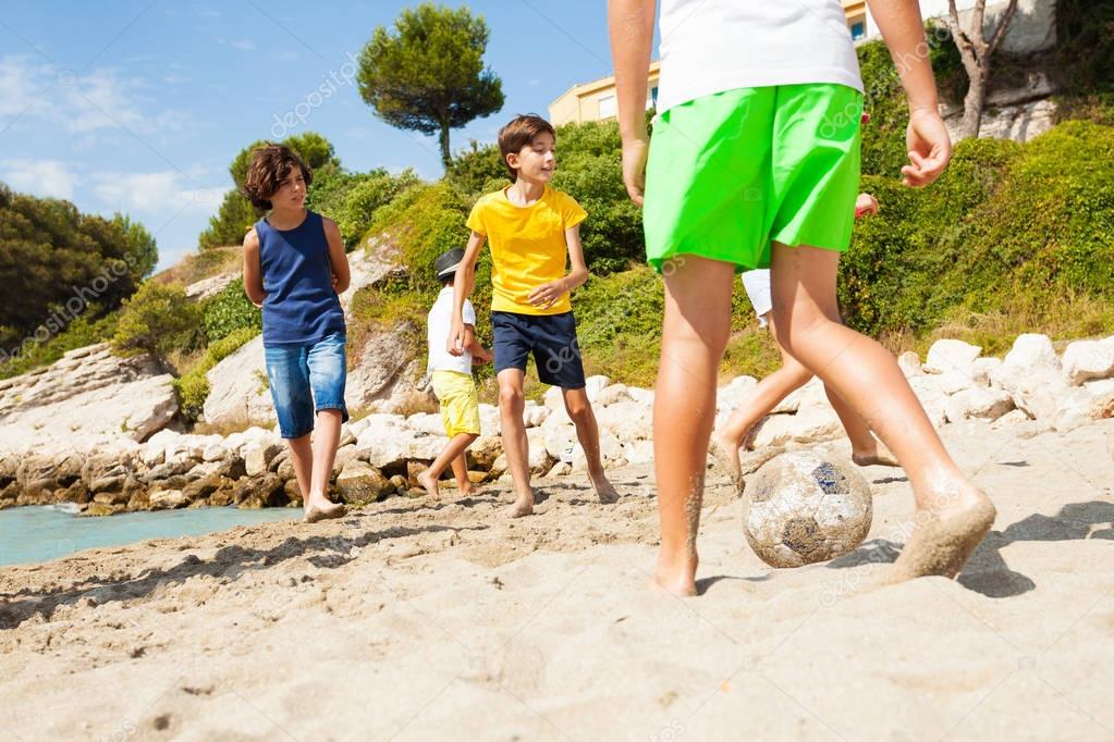 Group of kids playing football on sandy Mediterranean beach