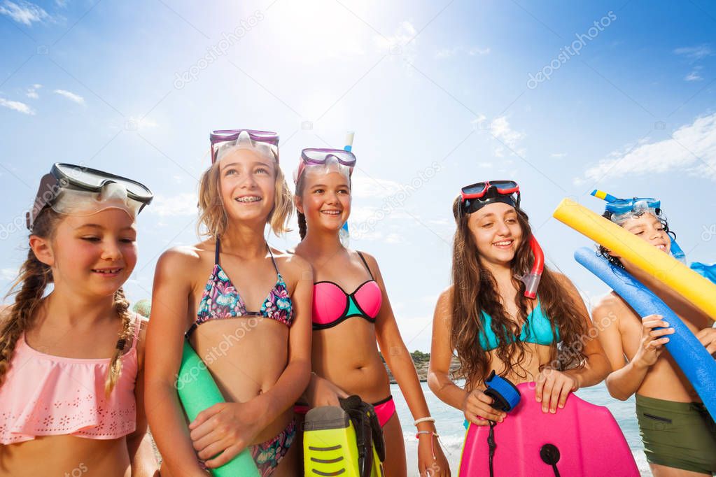 Girls and boy portrait in bikini with scuba masks stand over sky on sunny hot day on the beach