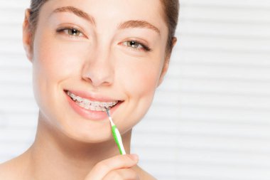 Yakın çekim portre mutlu güzel genç kadının onun diş brace tarafından interdental fırça Temizleme