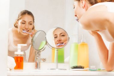 Diş telleri ile dişlerini fırçalama, banyo aynası önünde duran ve yansıma Image'da arıyorum güzel kadın