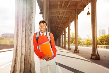 Beyaz ders kitapları, açık havada güneşli gün tutan mutlu Afrika öğrenci