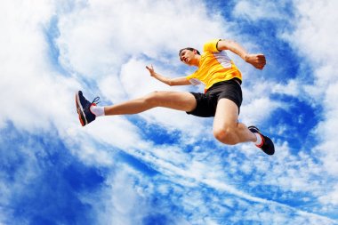 Sporcu karşı bulutlu gökyüzü atlama sırasında havada kalır