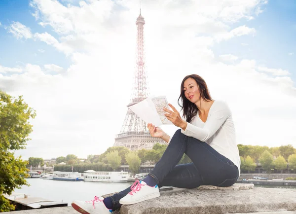 有吸引力的年轻妇女的肖像看着地图 而坐在对埃菲尔铁塔 — 图库照片