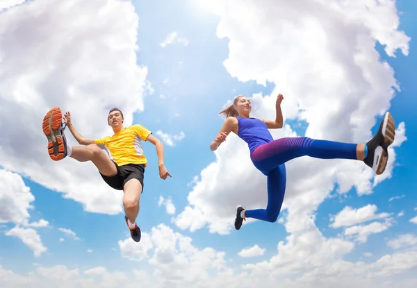 年轻运动员 男子和妇女在运动衫的底部的看法 保持在空气中 而跳跃对多云的天空 — 图库照片