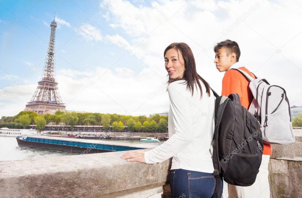 Caucasian woman and African man standing at the embankment of Seine River and looking at the Eiffel Tower, Paris