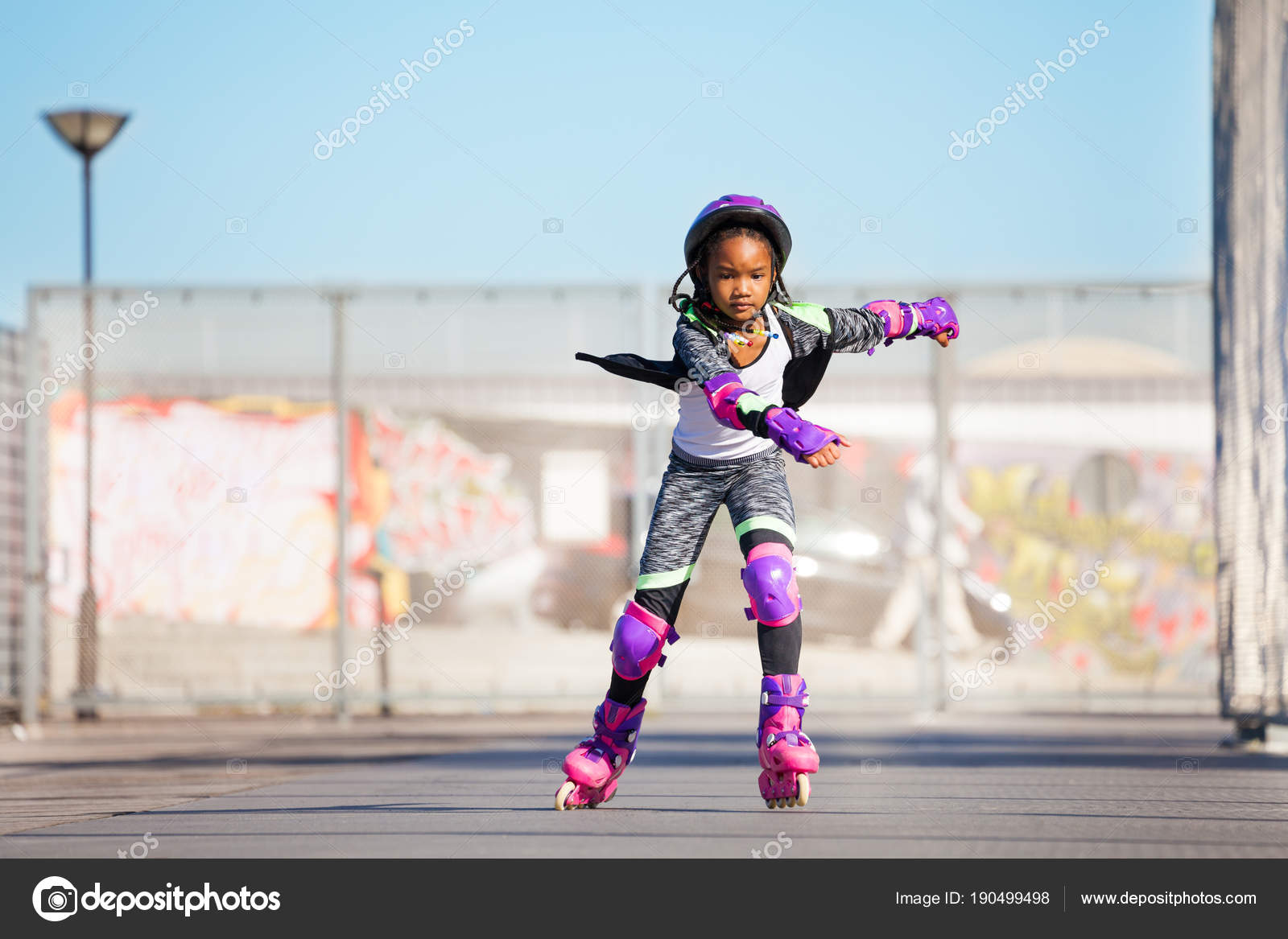 Enfant Fille Dans Un Casque En Rollers De Protection Dans Le Parc