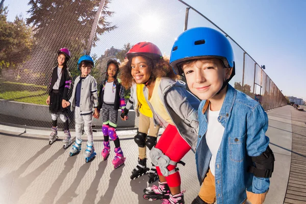 大群多民族的男孩和女孩 安全头盔的轮滑运动员 手持在户外体育场排队的手 — 图库照片