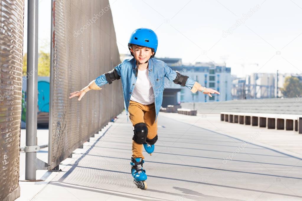 Preteen boy in helmet practicing rollerskating with his hands like wings at outdoor rollerdrome