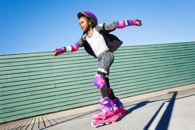Afrikalı kız, aktif roller patenci, hızlı açık rollerdrom sürme yan görünümü portresi
