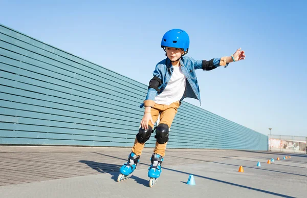 プレティーンの少年保護ギヤを身に着けている円錐形が付いている道にローラー スケートをする学習 — ストック写真