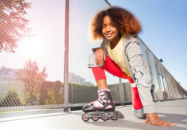 スケートパークで床でポーズ インライン スレートや保護具を着て幸せなアフリカ女の子 — ストック写真
