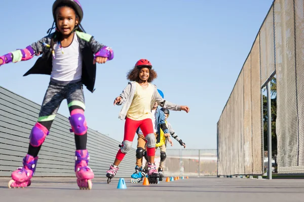 African girls, happy inline skaters, learning forward slalom at skate park at sunny day with friends