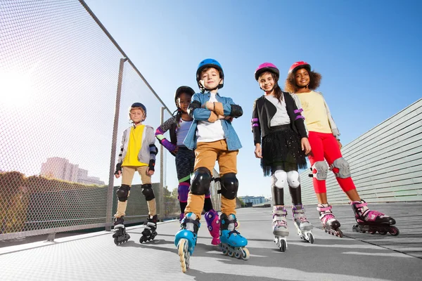 旱冰鞋中快乐多民族儿童的低角观和在阳光明媚的日子在体育场户外运动的防护装备 — 图库照片
