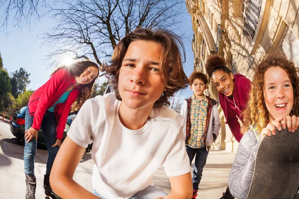 十代の男の子と女の子スケート ボードやローラーブレードは歩道に一緒に座っているとクローズ アップの肖像画 — ストック写真