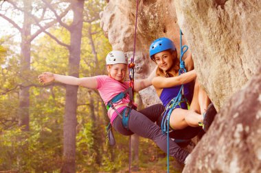 Portrait of two climbers abseiling training on steep rock in forest area clipart