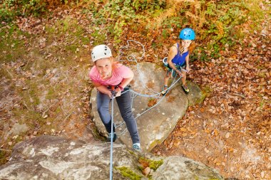 Kask abseiling eğitimi dik kaya orman alanında kadın eğitmen ile genç kız portresi Üstten Görünüm