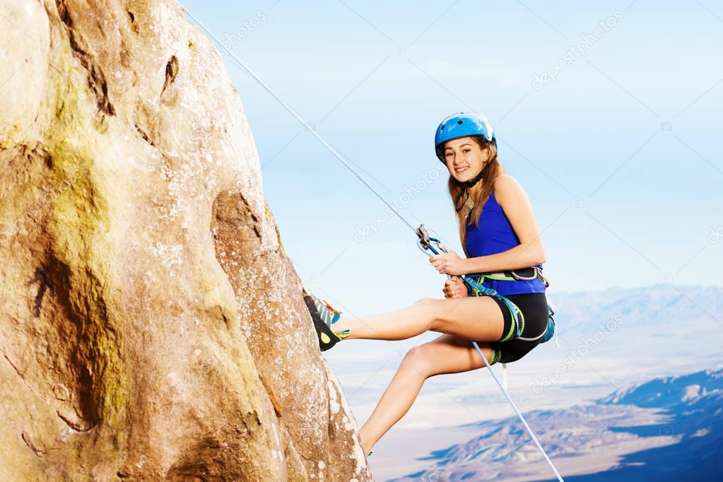Side view of teenage girl climber using technique of the abseil method of roping down