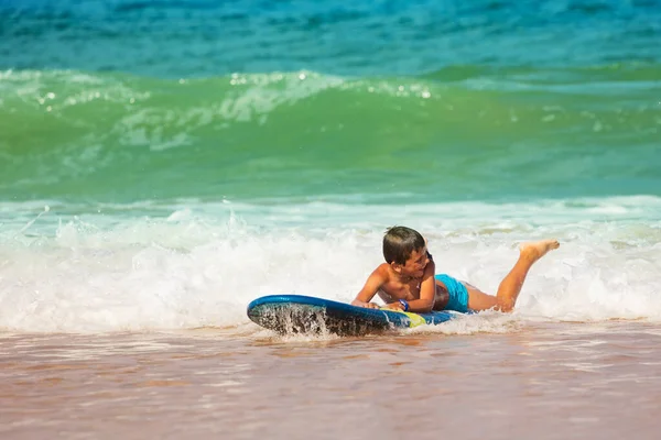 Menino deitado na borda da praia praticar movimentos de surf — Fotografia de Stock