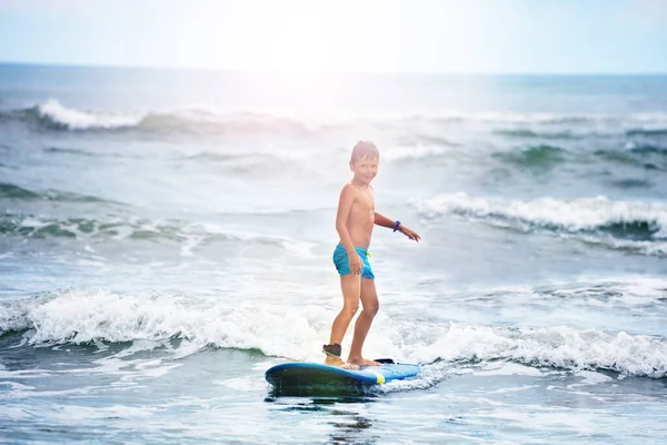 Liten pojke som står på surfbräda i vattnet — Stockfoto