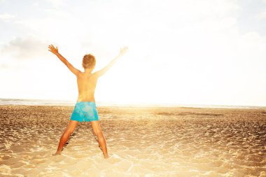 Boy look at see sunset beach with stretched hands