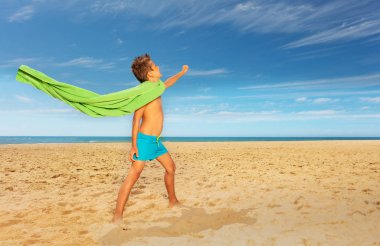 Boy pretend to be superhero with towel on sea
