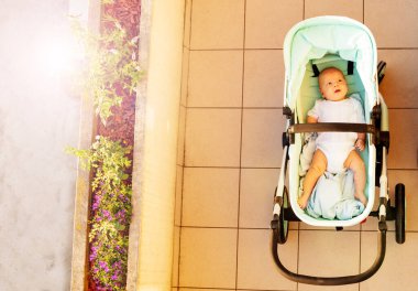 Cute infant boy in baby carriage view from above