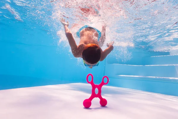 Piccolo ragazzo tuffarsi in profondità per raggiungere un giocattolo sul fondo della piscina — Foto Stock