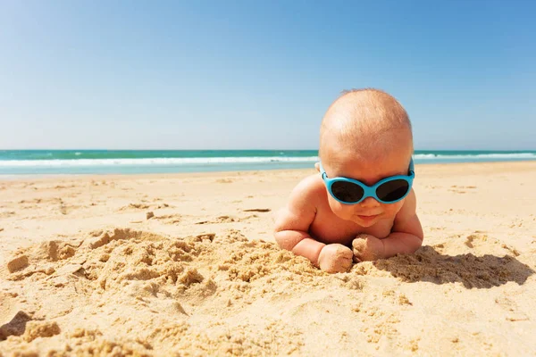 Portrait of little infant in sunglasses on a beach — Stockfoto