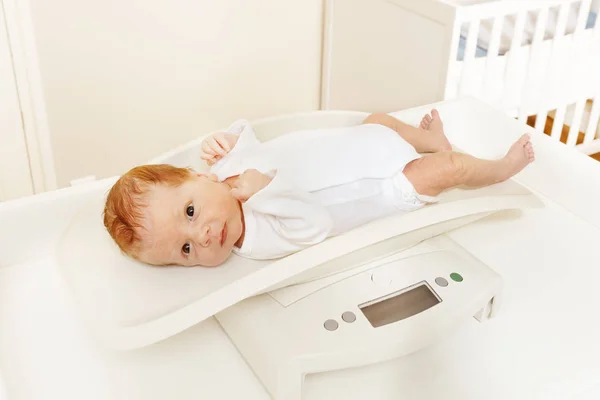 Pequeño niño acostado a escala para medir el cuerpo — Foto de Stock