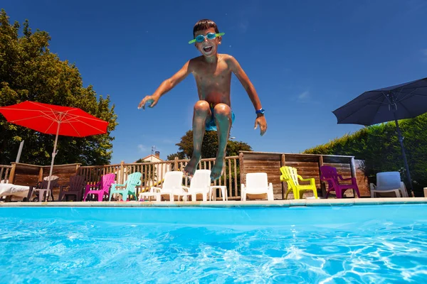 Кричащий счастливый мальчик прыгнул в бассейн — стоковое фото