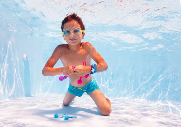 Boy swim underwater take toys in pool with googles — Stockfoto