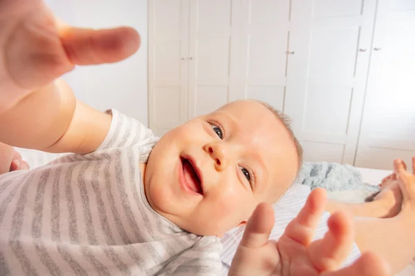 Bonito bebê rindo agarrando e olhando para a câmera — Fotografia de Stock