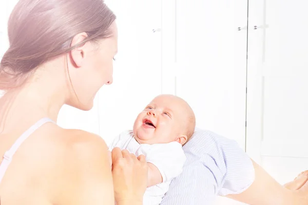 Счастливая мать играет и разговаривает с милым новорожденным младенцем — стоковое фото